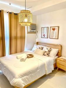 a bedroom with a large white bed with a chandelier at One-Bedroom and Studio Apartment near SM City , IT Park and Ayala Mall - NO PARKING at Bamboo Bay Community in Mandaue City +24 photos