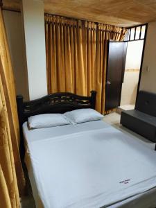 a bed with white sheets and pillows in a room at Merkezi Saray in Villavieja