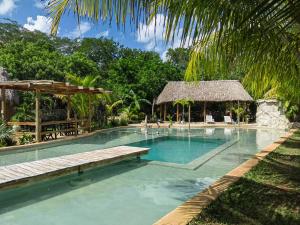 a swimming pool in a resort with a palm tree at Xkopek, Camping y Cabañas in Valladolid