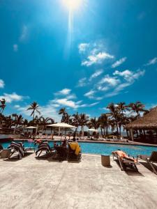 a resort with a pool and chairs and palm trees at Camino al Mar in Mazatlán