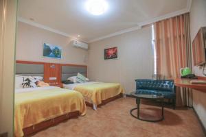 a hotel room with two beds and a chair at Zhangjiajie Tianmen Mountain Aribadi Inn in Zhangjiajie