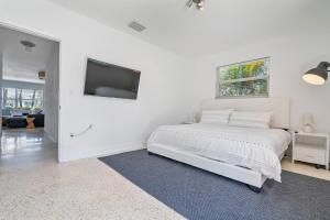 um quarto branco com uma cama e uma televisão de ecrã plano em Perfect Beach Home For A Family Getaway Wpool! em Miami Beach