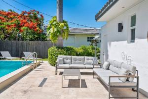 un patio con muebles blancos junto a una piscina en Perfect Beach Home For A Family Getaway Wpool!, en Miami Beach