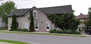 a brick house with a black roof on a street at Stone Carriage House in Picton