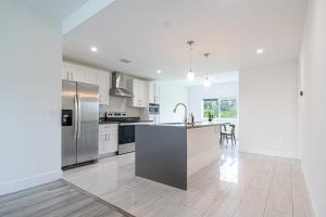 Una cocina con gabinetes blancos y electrodomésticos de acero inoxidable. en Perfect 3 Bed 2 Bath Apt W Free Parking, en Hallandale Beach