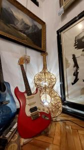 a red guitar hanging on a wall next to a lamp at HeArt of Old Town Guesthouse in Podgorica