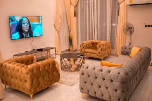 een woonkamer met een grote bank en 2 stoelen bij Sleek Luxury Homes in Kumasi