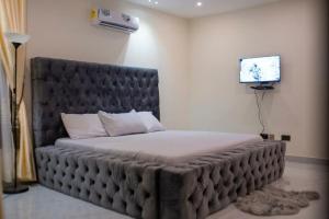 ein großes Bett in einem Zimmer mit einem TV in der Unterkunft Sleek Luxury Homes in Kumasi