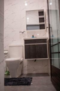 a bathroom with a toilet and a sink and a mirror at Sleek Luxury Homes in Kumasi