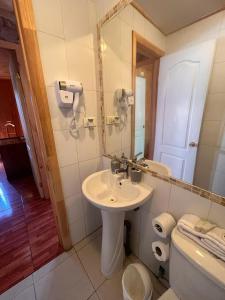 a bathroom with a sink and a mirror and a toilet at Cabañas Rukaparra in Pinto