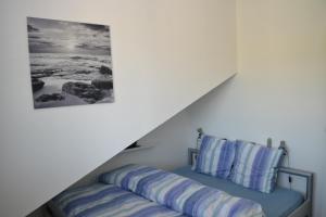 a bed with blue pillows sitting under a stairs at Two-bedroom Apartment for 4-5 guests with lake and mountain views in Emmetten