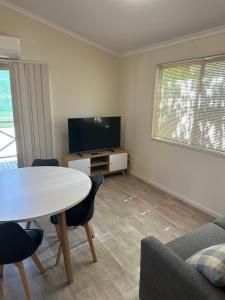 a living room with a table and a tv at Mudgee Riverside Park in Mudgee