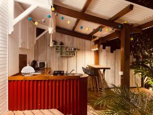 an outdoor kitchen with a red bar and a wooden wall at Les Coulirooms - Suite avec jacuzzi et grande terrasse in Sainte-Anne