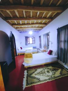 a large room with two beds and a rug at Riad pizzeria Marhaba in Akhendachou nʼAït Ouffi