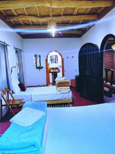 a room with two beds and a table and chairs at Riad pizzeria Marhaba in Akhendachou nʼAït Ouffi