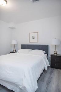 a bedroom with a large white bed with two lamps at The Oasis in Bowmanville