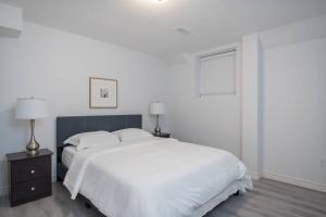 a white bedroom with a large bed and two lamps at The Oasis in Bowmanville