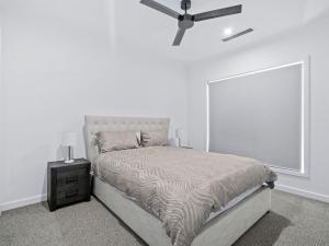 a white bedroom with a bed and a ceiling fan at 45 On Fairway in Yarrawonga +15 photos
