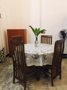 a dining room table with a vase with a plant on it at Raviya Place in Dickwella