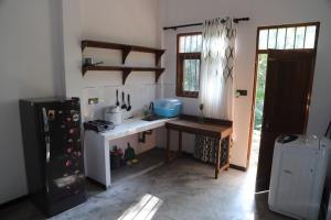 a kitchen with a counter and a refrigerator and a table at Raviya Place in Dickwella