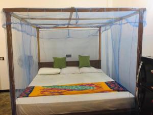 a bedroom with a canopy bed with blue drapes at Raviya Place in Dickwella