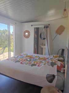 a bedroom with a bed with a colorful blanket on it at Chambres d'hôtes Tontouta Tamoa in Païta