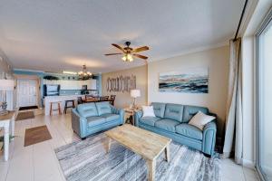 a living room with two blue chairs and a ceiling fan at Ocean Villa 1104 in Panama City Beach