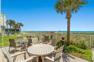 a patio with a table and chairs and a palm tree at Ocean Villa 1104 in Panama City Beach