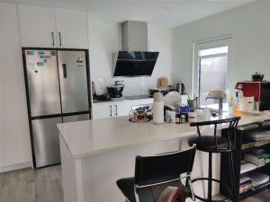 uma cozinha com um frigorífico, uma mesa e cadeiras em LilyのHome Elegant Retreat near Riccarton Mall em Christchurch
