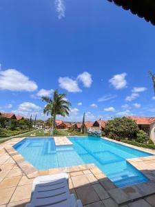 a pool with two chairs and a palm tree at Chalé Gravatá - Privê Jardim de Marie in Gravatá