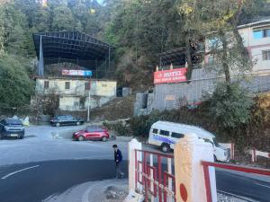 a man standing next to a parking lot with cars at Hotel The Amar Grand in Mussoorie