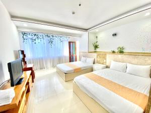 a hotel room with two beds and a television at ZoZo house - Homestay Bai Sau in Vung Tau