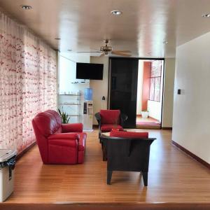 uma sala de estar com duas cadeiras vermelhas e uma mesa em Tessie's Home Stay Bed & Breakfast em Puerto Princesa
