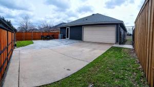 a house with a garage next to a fence at Family home sleeps 10! Private yard & king beds! in Dallas