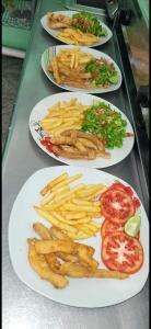 cuatro platos de comida con patatas fritas y tomates en Esmeralda, en Ojo de Agua