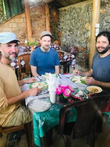 tres hombres sentados en una mesa comiendo comida en DILSHAN HOTEL Diyaluma, en Koslanda
