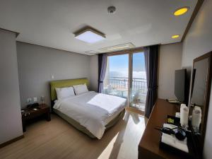 - une chambre avec un lit et une vue sur l'océan dans l'établissement Mud Beach Hotel, à Boryeong