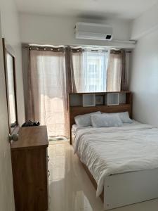 a bedroom with a large bed and a window at Bright & Breezy 2 BR Unit with Balcony in Manila