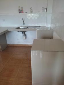 een witte keuken met een wastafel en een houten vloer bij Hospedaje Camila in Pucallpa
