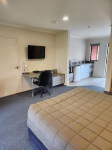 a hotel room with a bed and a desk and a television at Oak Estate Motor Lodge in Greytown
