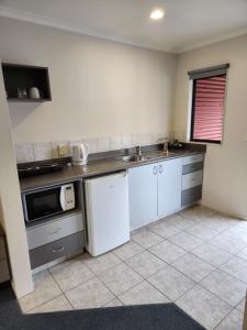 a kitchen with a sink and a microwave at Oak Estate Motor Lodge in Greytown