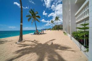 a beach with palm trees and a building at Beachfront Condo in Paradise in Waianae