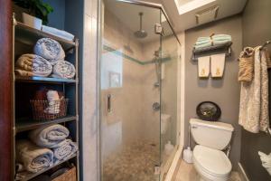 a bathroom with a shower and a toilet and towels at Beachfront Condo in Paradise in Waianae
