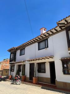 una motocicleta estacionada frente a una casa blanca en Hostal El Palacio Del Descanso en Villa de Leyva