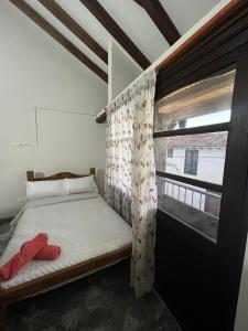 ein kleines Schlafzimmer mit einem Bett und einem Fenster in der Unterkunft Hostal El Palacio Del Descanso in Villa de Leyva