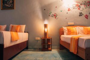 a bedroom with two beds and a lamp on a table at Shell Resort in Arugam Bay