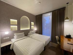 a hotel room with two beds and a window at Azana Essence Sanggabuana Bogor in Kamparganya