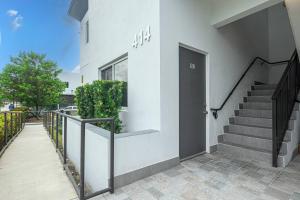 une maison blanche avec un escalier et une porte dans l'établissement Comfy 3 Bed 2 Bath Apt W Free Parki, à Hallandale Beach