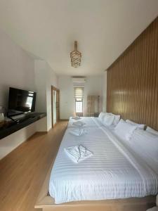 1 cama blanca grande en una habitación con TV en RINA Poolvilla (รินะ พูลวิลล่า) en Hat Yai