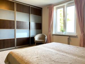a bedroom with a bed and a chair and a window at Helska Space by Grand Apartments in Sopot